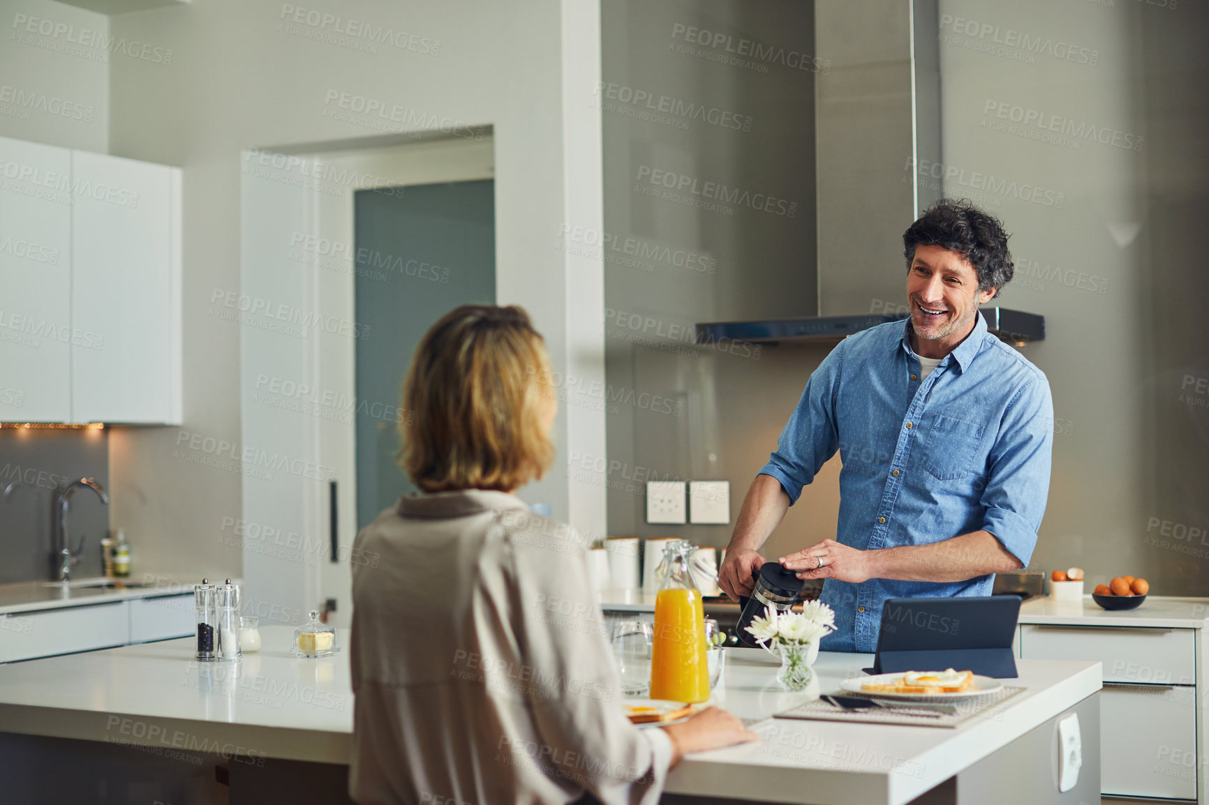Buy stock photo Couple, smile and discussion with breakfast in kitchen for routine, food or nutrition for wellness. Mature people, talk and morning meal in home with orange juice, bonding together with balanced diet