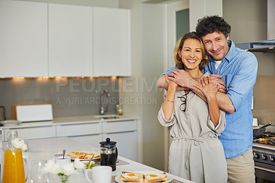 Buy stock photo Shot of a mature couple hugging while preparing breakfast together at home