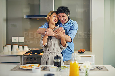 Buy stock photo Shot of a mature couple hugging while preparing breakfast together at home