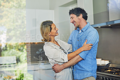 Buy stock photo Shot of a mature couple hugging in the kitchen at home