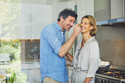 Buy stock photo Shot of a mature man giving his wife a taste of his cooking at home