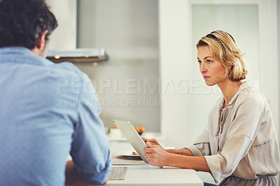Buy stock photo Shot of a mature woman using a digital tablet while having breakfast with her husband at home