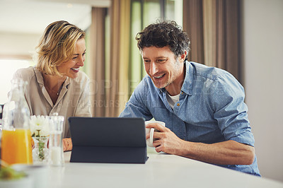 Buy stock photo Shot of a mature couple using a digital tablet while having breakfast at home