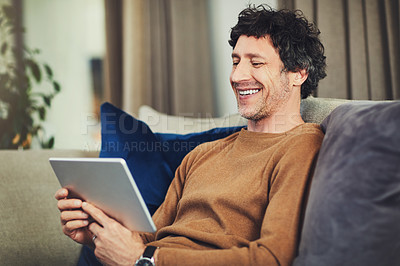 Buy stock photo Shot of a mature man using a digital tablet on the sofa at home