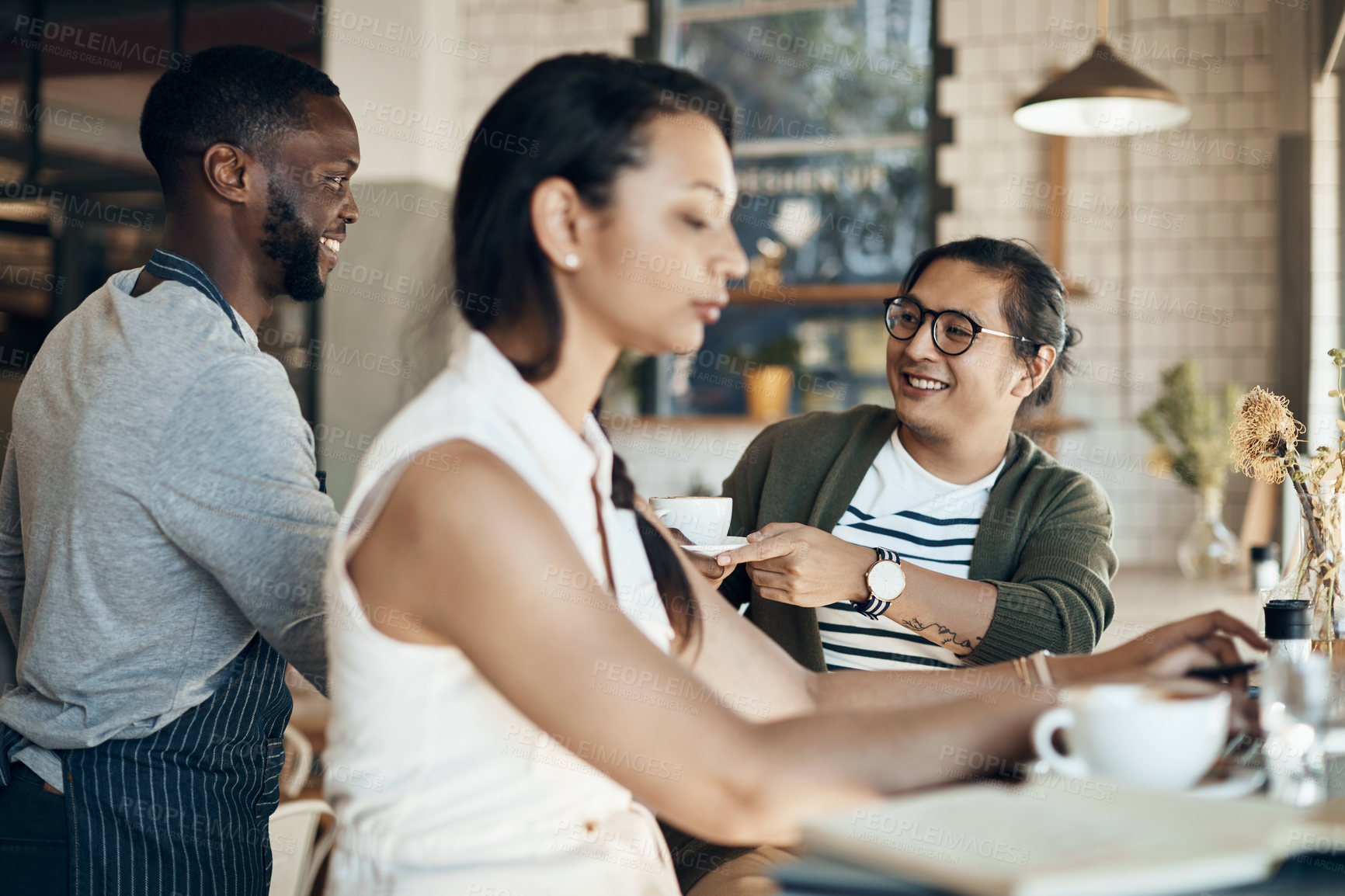 Buy stock photo Cropped shot of a handsome young businessman sitting with a female colleague and getting a coffee in a cafe