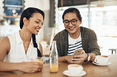 Buy stock photo Cropped shot of a handsome young man sitting with a female friend and using his cellphone in a cafe