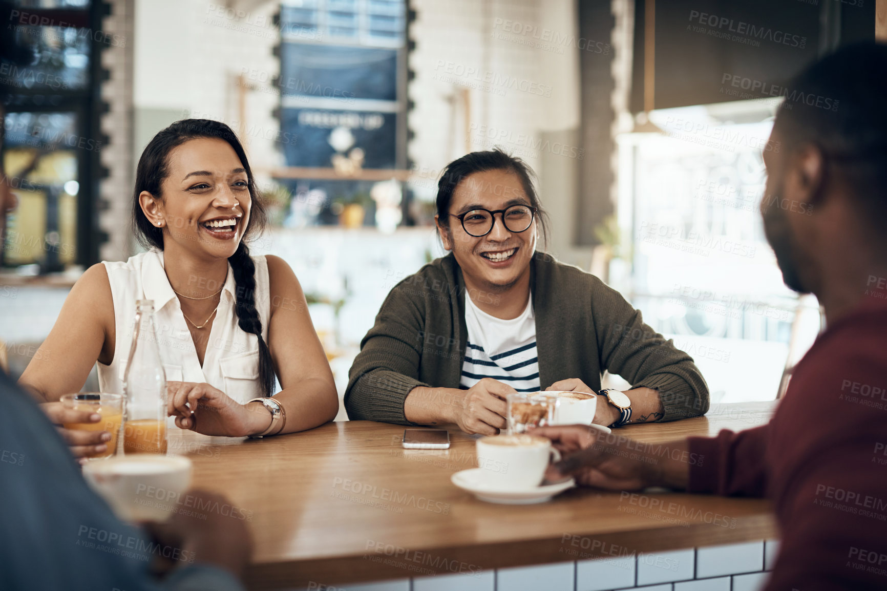 Buy stock photo Cropped shot of a young group of friends sitting together and bonding in a cafe during the day