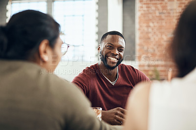 Buy stock photo Cropped shot of a handsome young man sitting and enjoying a day with his friends in a cafe