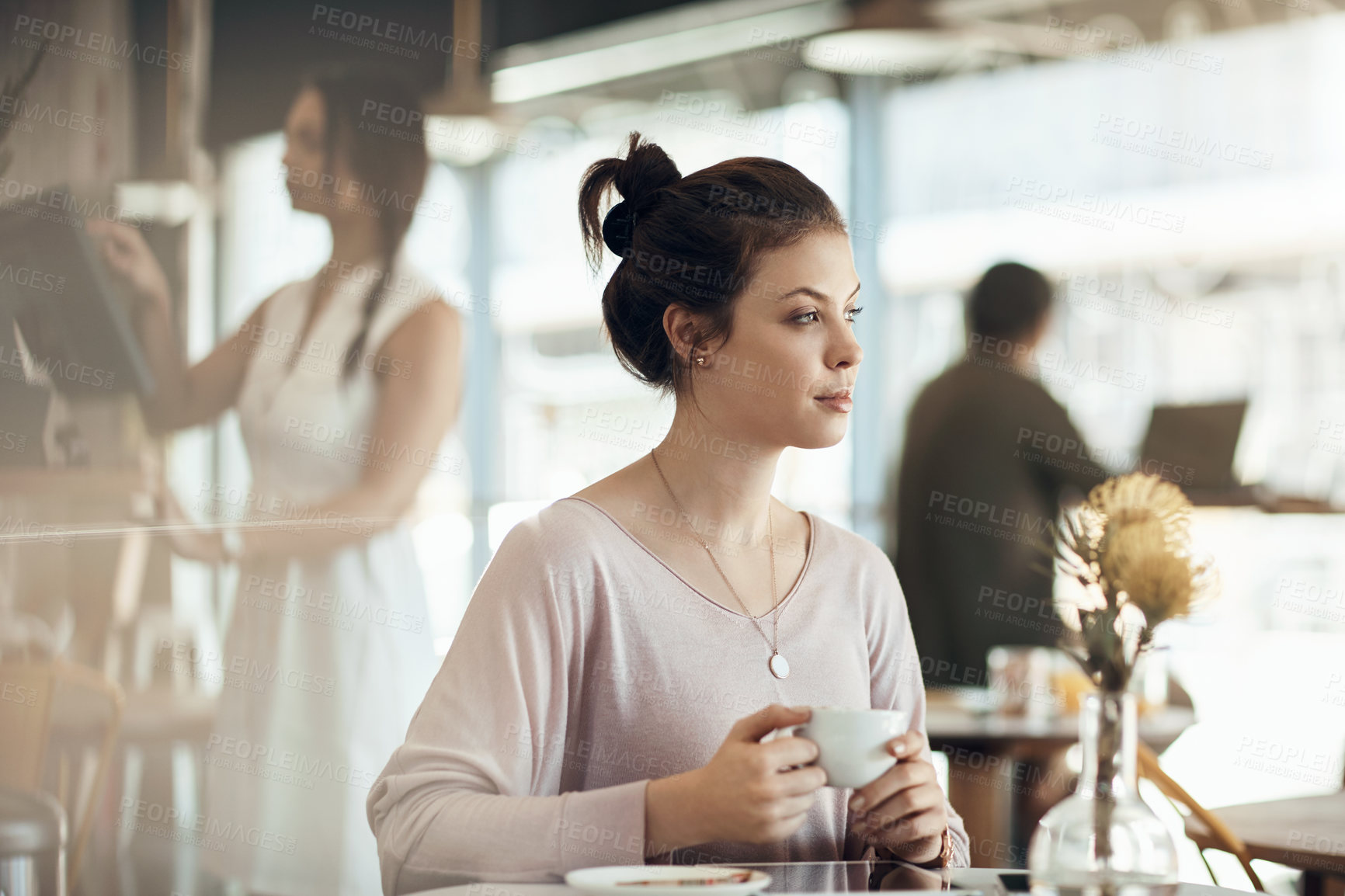 Buy stock photo Cropped shot of an attractive young woman sitting on her own and enjoying a cup of coffee in a cafe