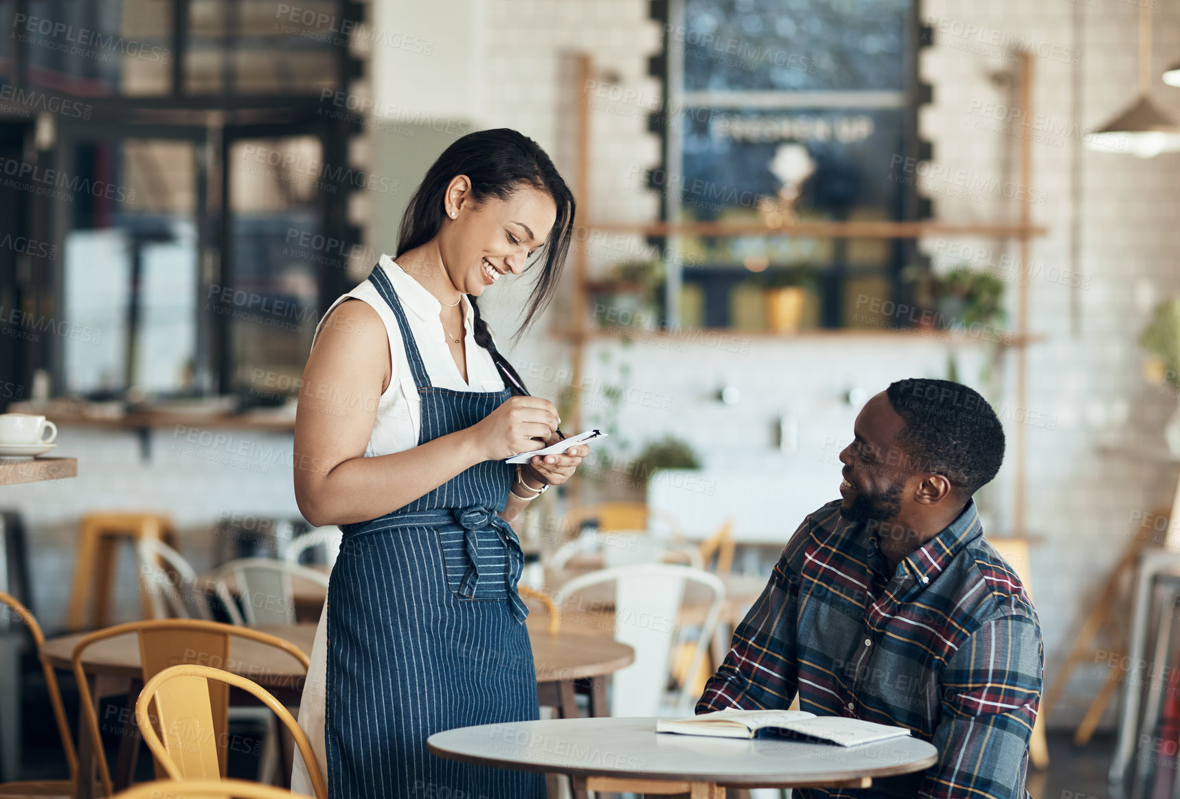 Buy stock photo Cropped shot of an attractive young waitress taking down an order for a male customer in the cafe