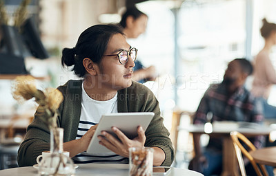 Buy stock photo Cropped shot of a handsome young businessman sitting and looking contemplative while working on his tablet in a cafe