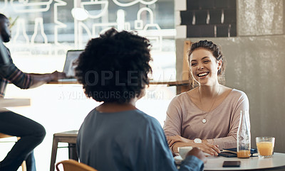 Buy stock photo Cropped shot of two attractive young women sitting together and bonding at a cafe during the day