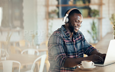Buy stock photo Cropped shot of a handsome young businessman wearing headphones to listen to music and using his computer in a cafe