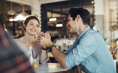 Buy stock photo Cropped shot of an affectionate young couple sitting together and holding hands during a coffee date in a cafe
