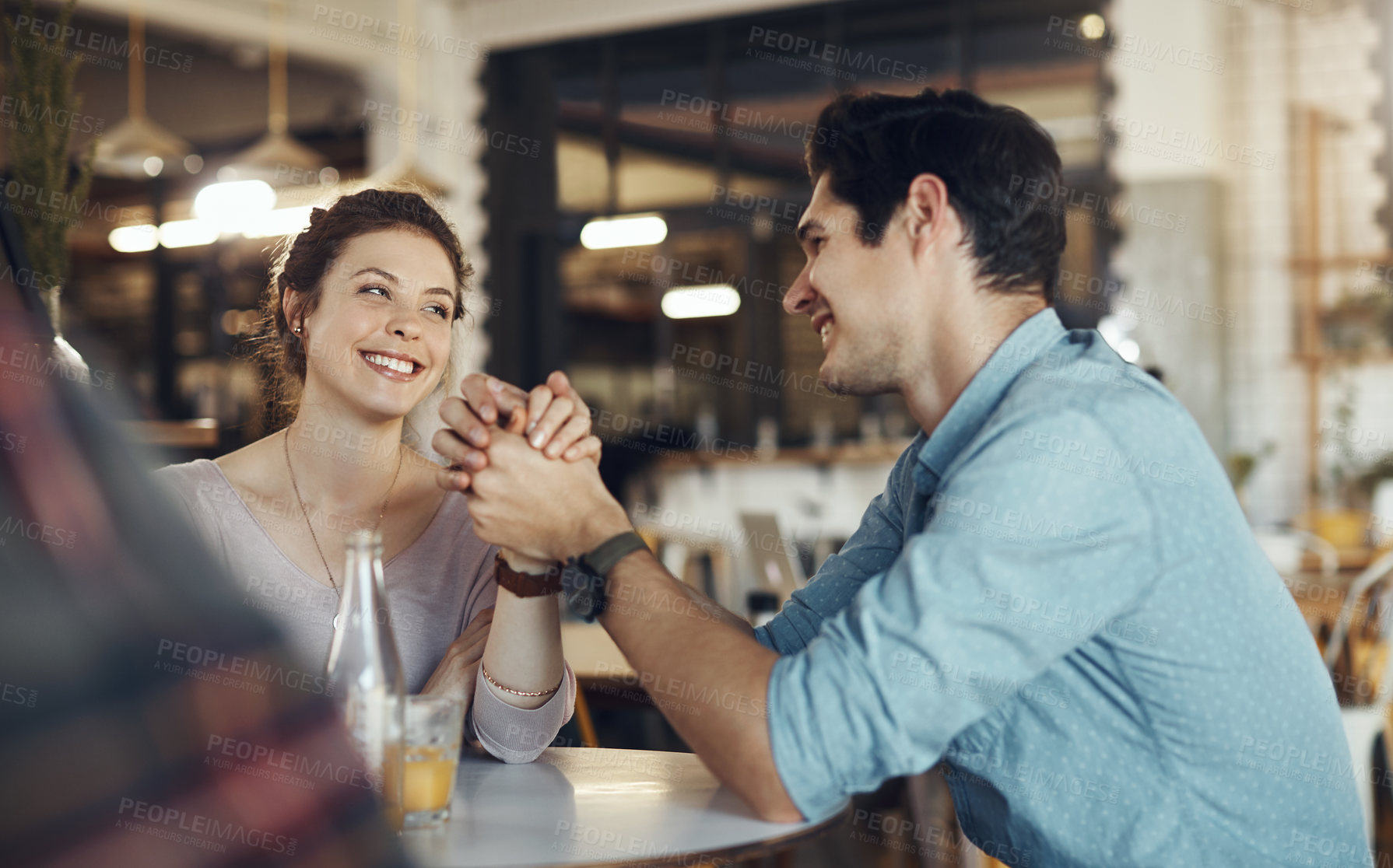 Buy stock photo Cropped shot of an affectionate young couple sitting together and holding hands during a coffee date in a cafe