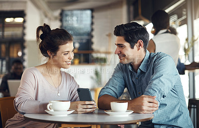 Buy stock photo Cropped shot of a happy couple sitting together and using a cellphone during a coffee date in a cafe