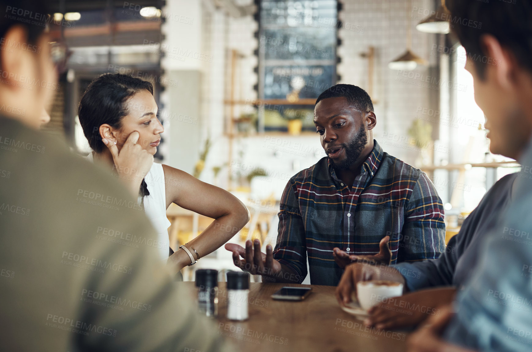 Buy stock photo Cropped shot of a diverse group of businesspeople sitting together and having a discussion in a coffee shop