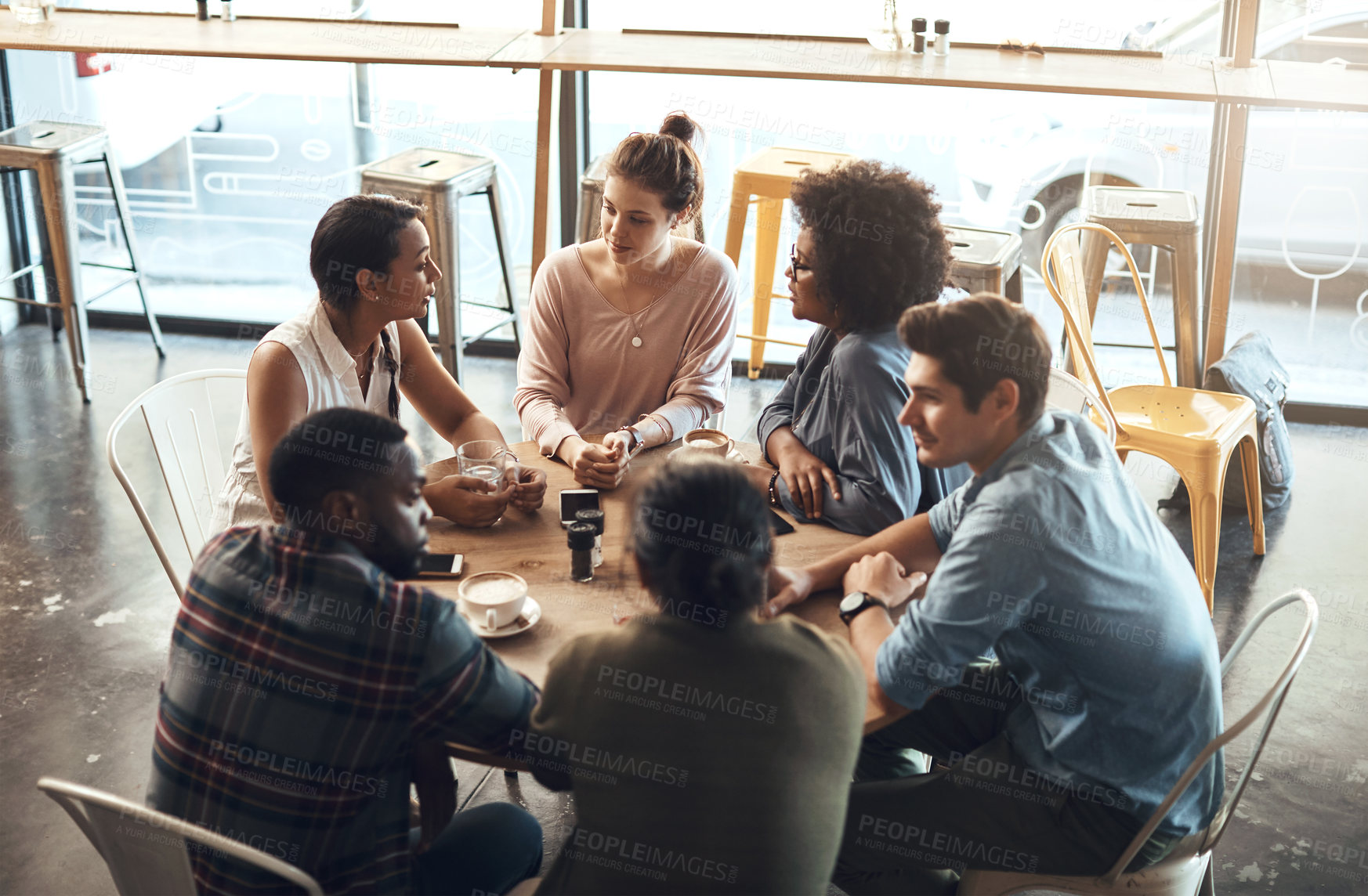Buy stock photo Cropped shot of a diverse group of businesspeople sitting together and having a discussion in a coffee shop
