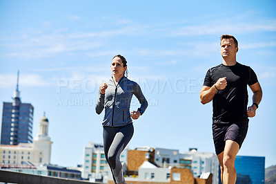 Buy stock photo Shot of two sporty young people out for a run in the city
