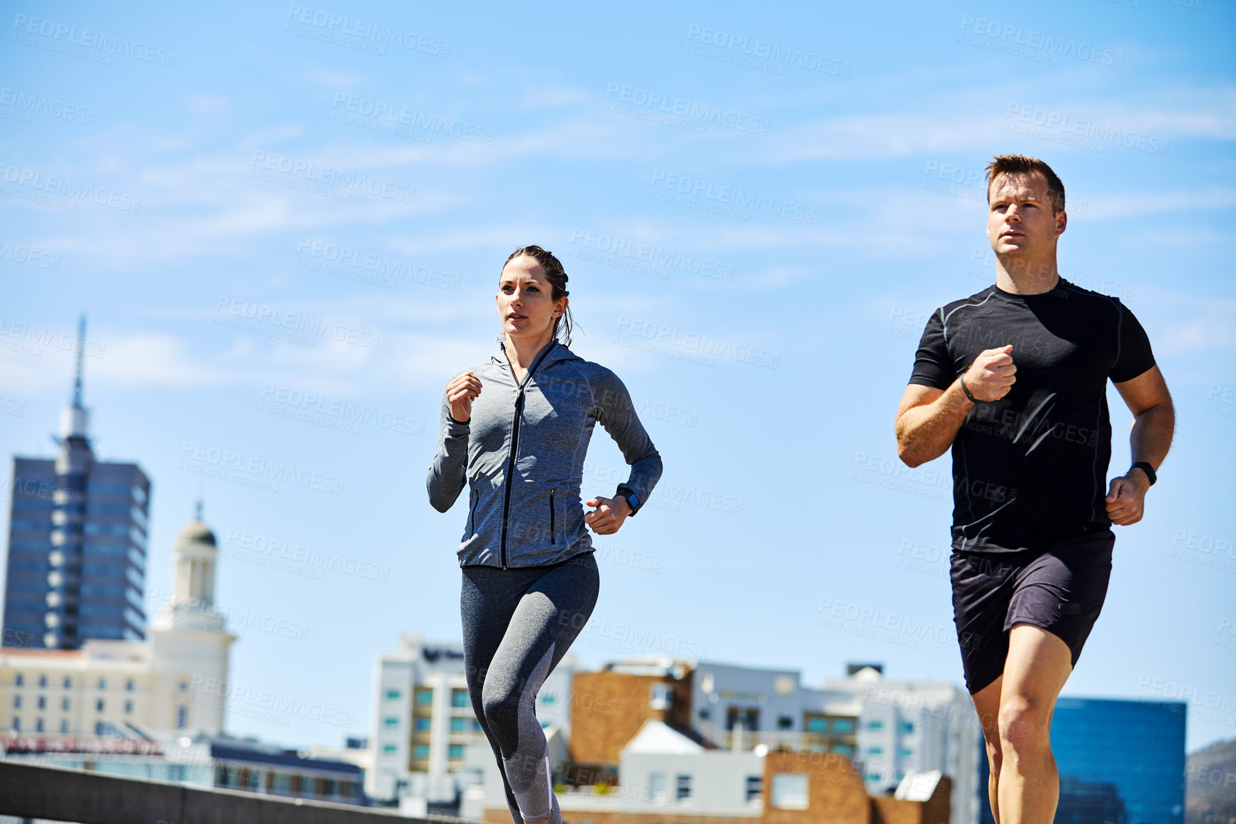 Buy stock photo Shot of two sporty young people out for a run in the city