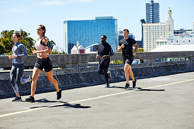 Buy stock photo Shot of a group of sporty young people out for a run in the city