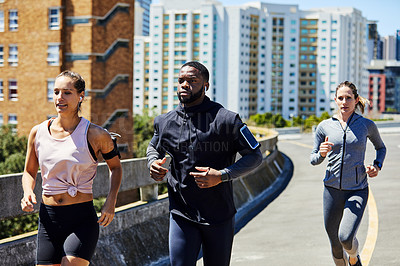 Buy stock photo Shot of a group of sporty young people out for a run in the city