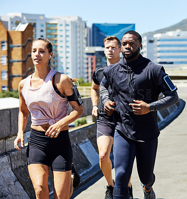 Buy stock photo Shot of a group of sporty young people out for a run in the city