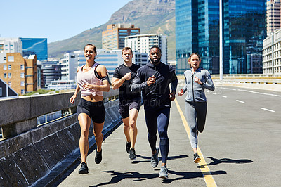 Buy stock photo Shot of a group of sporty young people out for a run in the city