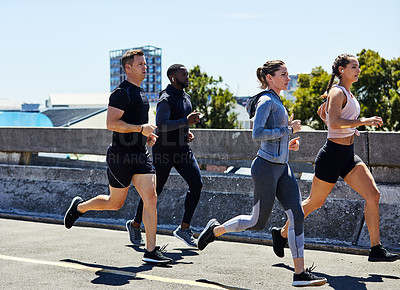Buy stock photo Shot of a group of sporty young people out for a run in the city