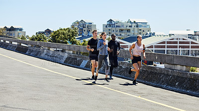 Buy stock photo Shot of a group of sporty young people out for a run in the city