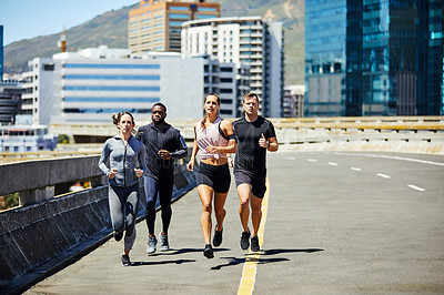Buy stock photo Shot of a group of sporty young people out for a run in the city
