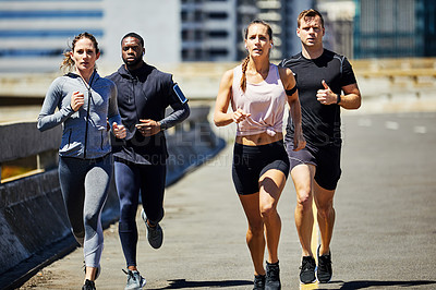 Buy stock photo Shot of a group of sporty young people out for a run in the city