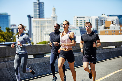 Buy stock photo Shot of a group of sporty young people out for a run in the city
