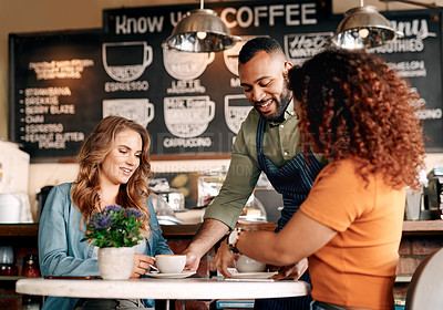 Buy stock photo Shot of a waiter serving two young women in a cafe