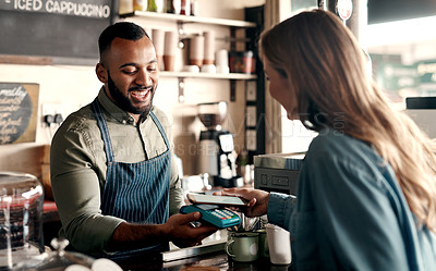 Buy stock photo Shot of a young man accepting a digital payment from a customer in a cafe