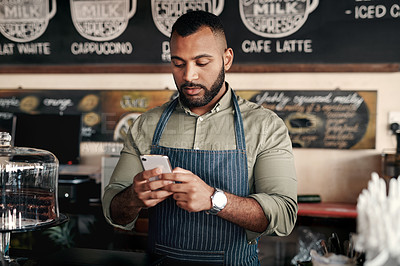 Buy stock photo Shot of a young man using a cellphone while working in a cafe