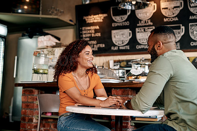 Buy stock photo Shot of a young couple holding hands while sitting at a table in a cafe