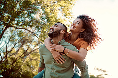 Buy stock photo Shot of a young man giving his girlfriend a piggyback ride outdoors