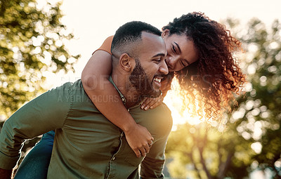 Buy stock photo Shot of a young man giving his girlfriend a piggyback ride outdoors