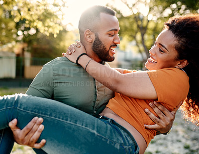 Buy stock photo Shot of a young man carrying his girlfriend outdoors