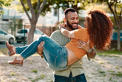 Buy stock photo Shot of a young man carrying his girlfriend outdoors