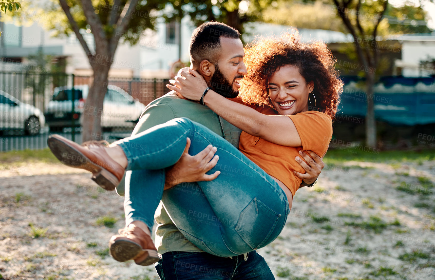 Buy stock photo Shot of a young man carrying his girlfriend outdoors