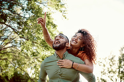 Buy stock photo Shot of a young man giving his girlfriend a piggyback ride outdoors