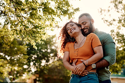 Buy stock photo Shot of a young couple cuddling each other outdoors