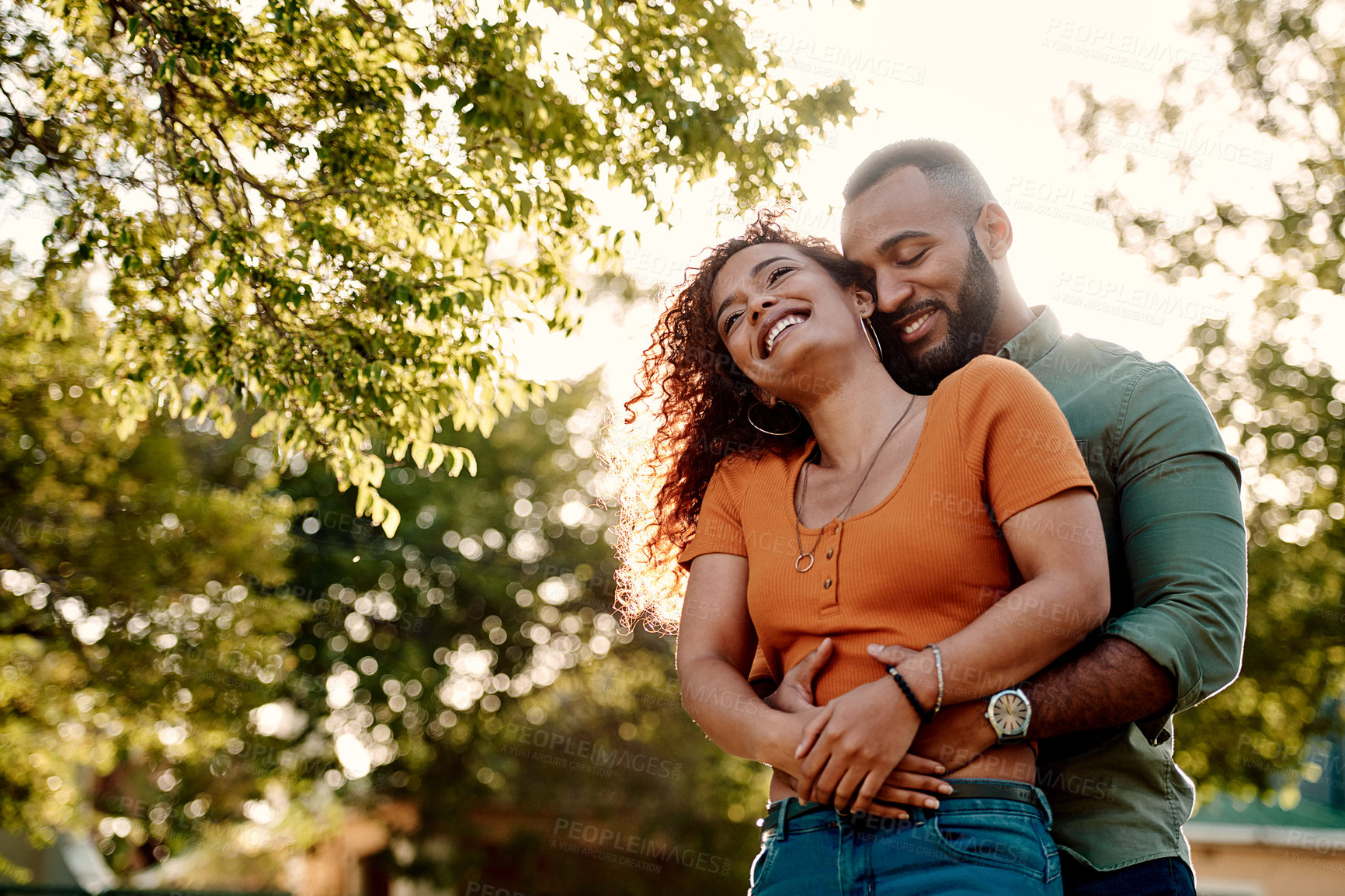 Buy stock photo Shot of a young couple cuddling each other outdoors