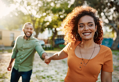 Buy stock photo Shot of a young woman holding her boyfriend's hand while walking together in a park