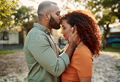 Buy stock photo Shot of a young man giving his girlfriend a kiss on the forehead outdoors