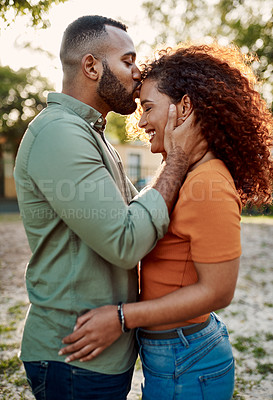Buy stock photo Shot of a young man giving his girlfriend a kiss on the forehead outdoors