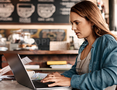 Buy stock photo Shot of a young woman working on a laptop in a cafe