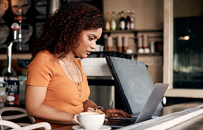 Buy stock photo Shot of a young woman working on a laptop in a cafe